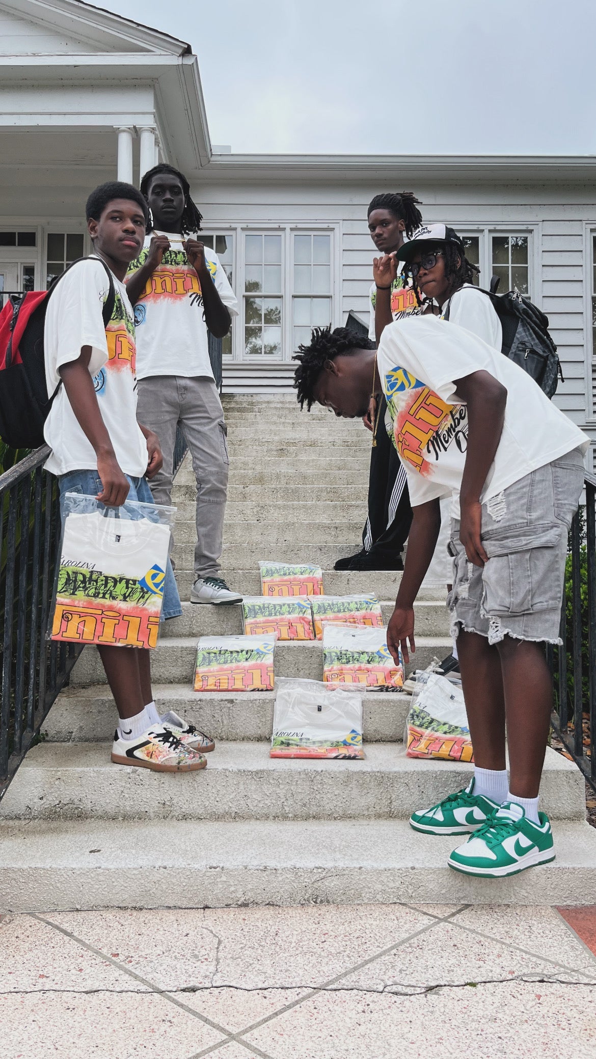 Uni1y Retro Street Tee group on steps with packaged shirts