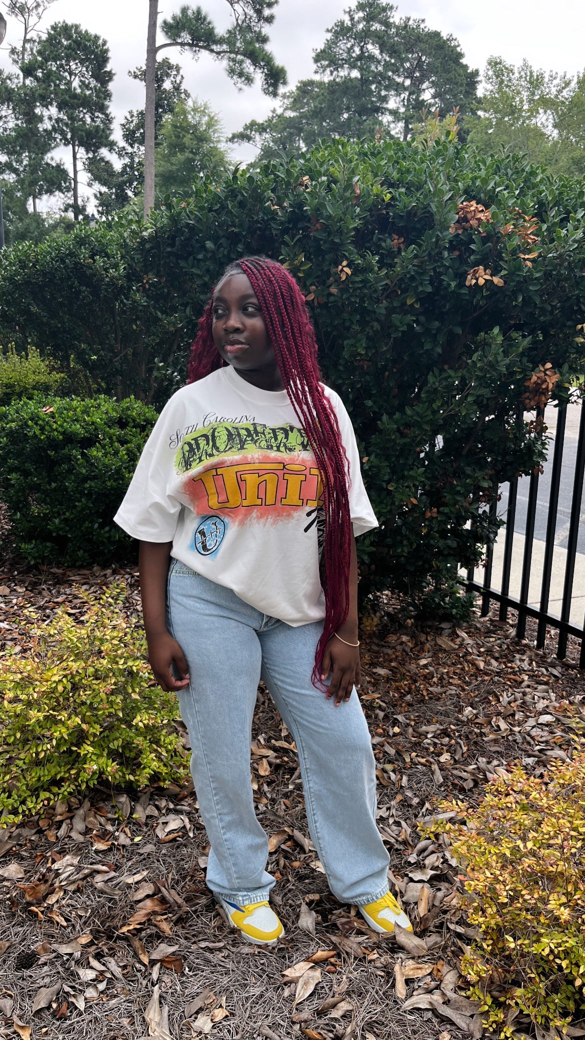 Uni1y Retro Street Tee worn by model in front of bushes